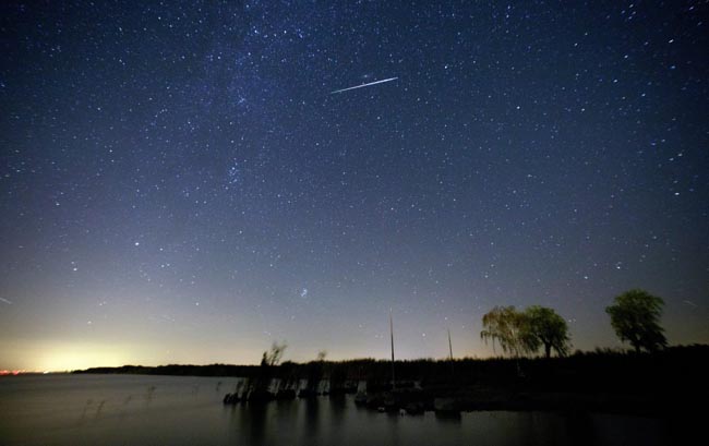 epa05475900 A picture taken with a slow shutter shows a meteor moving past stars in the night sky over lake Neusiedlersee near Moerbisch am See, around 70 km southeast of Vienna, Austria, early 12 August, 2016. The Perseid meteor shower is seen every August when the Earth passes through a stream of space debris left by Comet Swift-Tuttle. EPA/LISI NIESNER